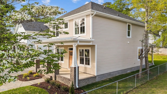 view of home's exterior featuring covered porch, roof with shingles, and fence