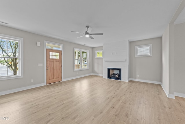 unfurnished living room with baseboards, light wood-style floors, ceiling fan, and a large fireplace