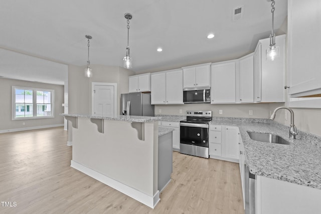 kitchen featuring light wood-type flooring, appliances with stainless steel finishes, white cabinets, and a sink