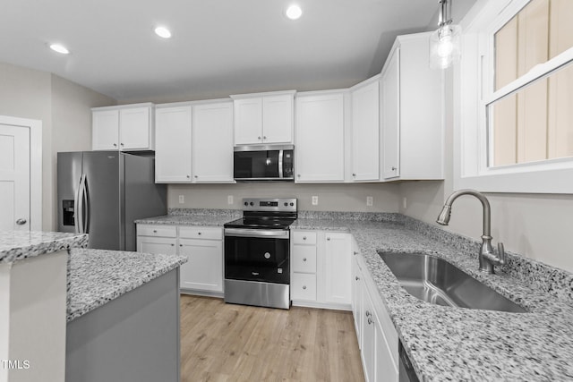 kitchen with recessed lighting, light wood finished floors, a sink, white cabinetry, and stainless steel appliances