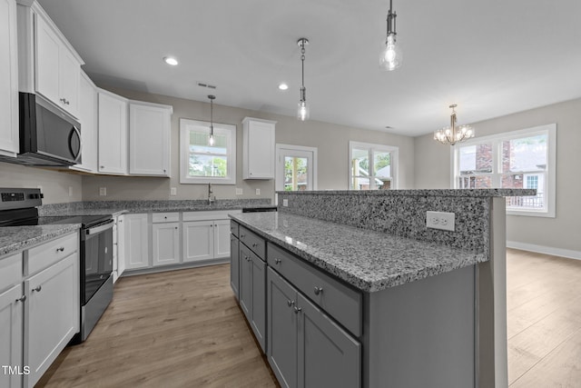 kitchen with stainless steel electric stove, gray cabinets, a notable chandelier, a kitchen island, and light wood-style floors