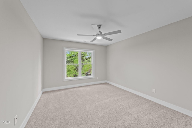 spare room with baseboards, ceiling fan, and carpet