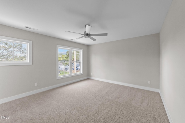 carpeted empty room with ceiling fan, baseboards, and visible vents