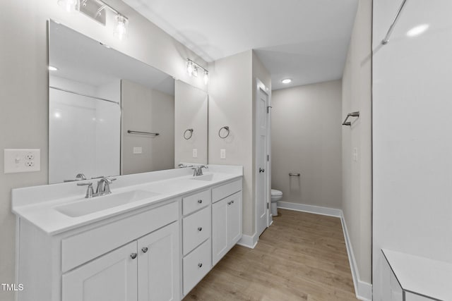 full bath featuring a sink, toilet, baseboards, and wood finished floors