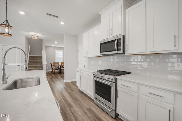 712 Emmer St, Rolesville, NC 27571 - kitchen with stainless steel appliances, a sink, backsplash, light wood-style floors, and white cabinets