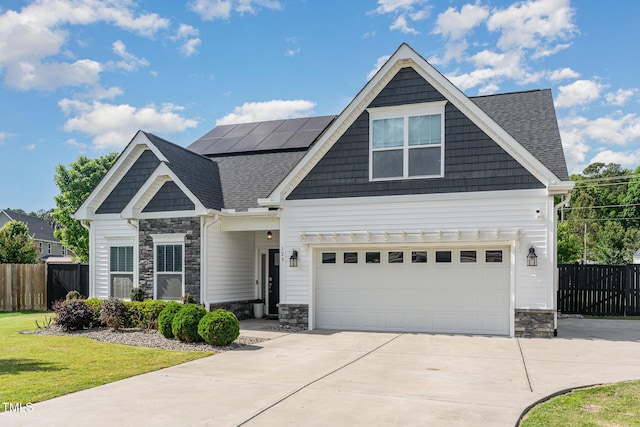 craftsman-style house with stone siding, roof mounted solar panels, concrete driveway, and a shingled roof