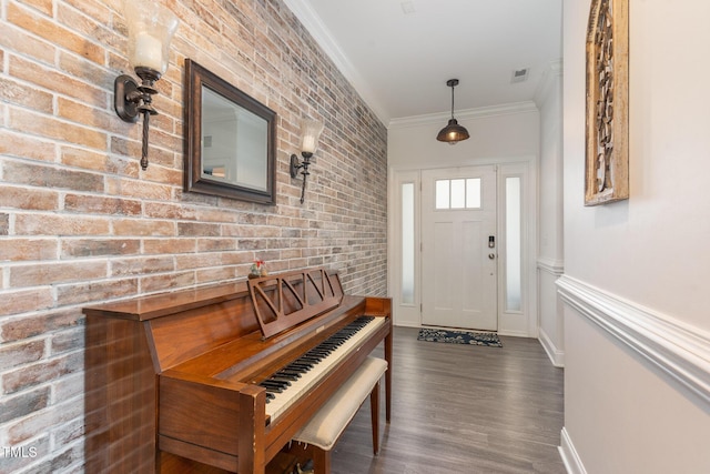entrance foyer featuring crown molding, wood finished floors, brick wall, and baseboards