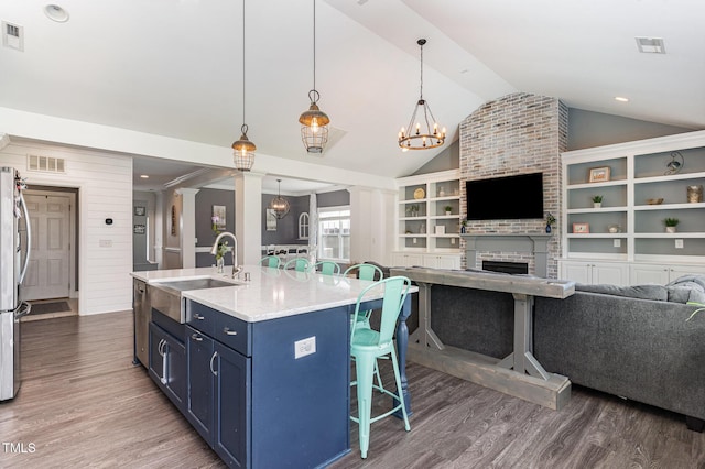 kitchen featuring a sink, blue cabinetry, vaulted ceiling, a kitchen bar, and dark wood-style floors