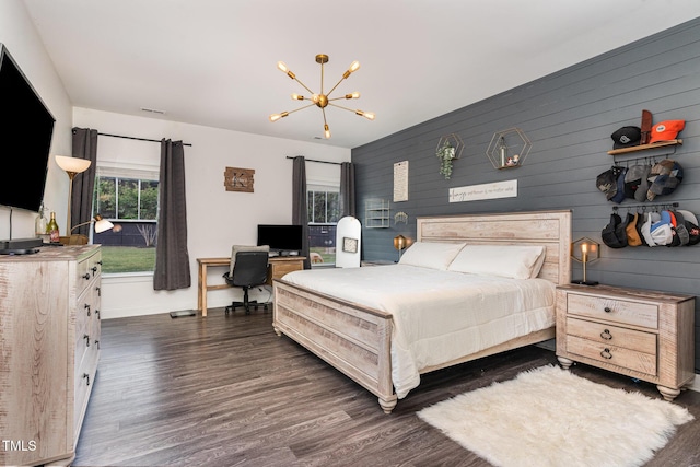 bedroom with a chandelier, dark wood finished floors, a desk, baseboards, and wooden walls