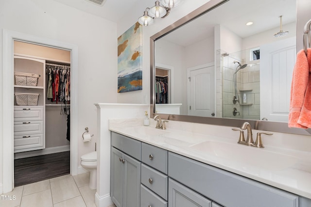 bathroom featuring a stall shower, tile patterned floors, double vanity, toilet, and baseboards
