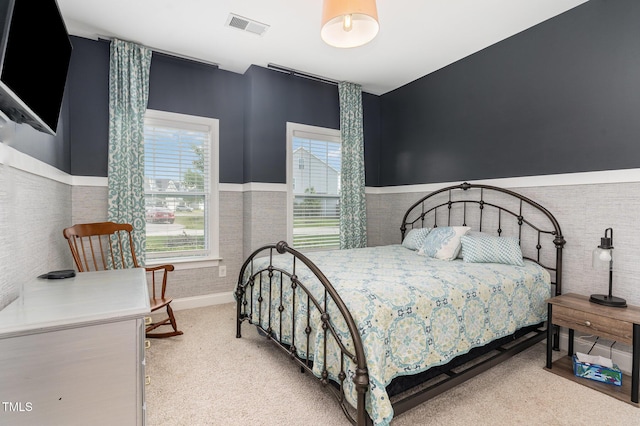 bedroom with a wainscoted wall and light carpet