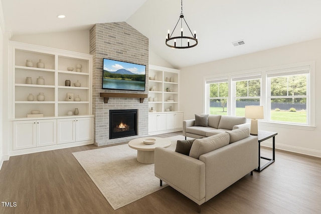 living area with vaulted ceiling, wood finished floors, a chandelier, a fireplace, and baseboards