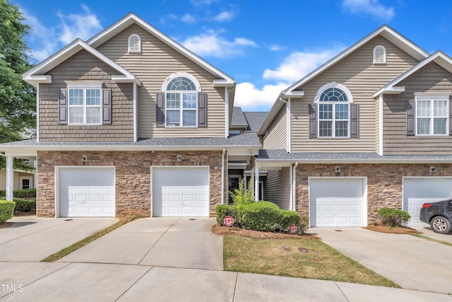 view of property featuring stone siding, driveway, and an attached garage