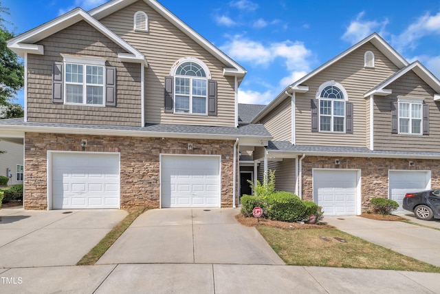 townhome / multi-family property featuring stone siding, a garage, and concrete driveway