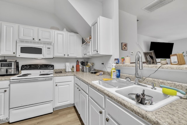 kitchen featuring white appliances, a sink, white cabinets, light wood finished floors, and vaulted ceiling