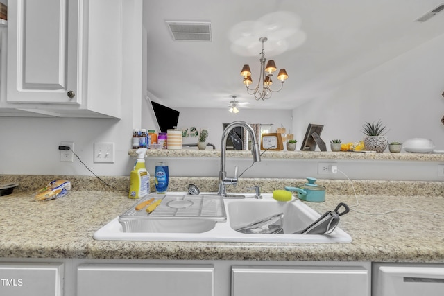 kitchen with a sink, a chandelier, white cabinets, and light countertops