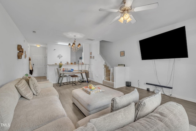 living room featuring a chandelier, stairs, wood finished floors, a ceiling fan, and baseboards