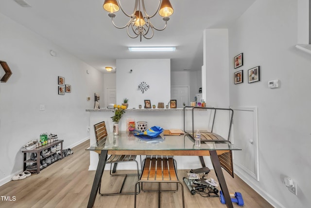 dining room with wood finished floors, a chandelier, and baseboards