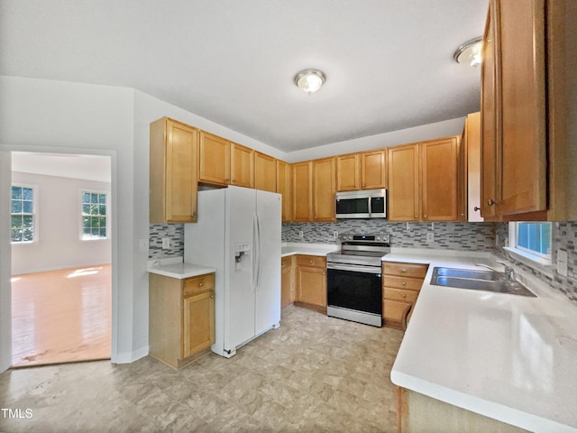 kitchen with light countertops, tasteful backsplash, appliances with stainless steel finishes, and a sink