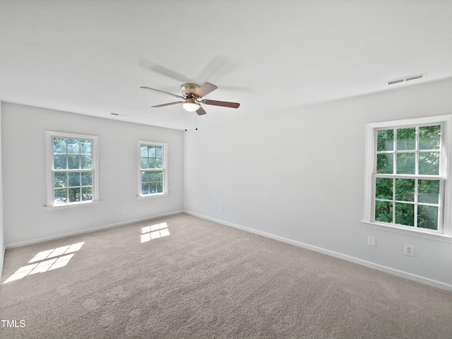 carpeted empty room featuring visible vents, baseboards, and ceiling fan