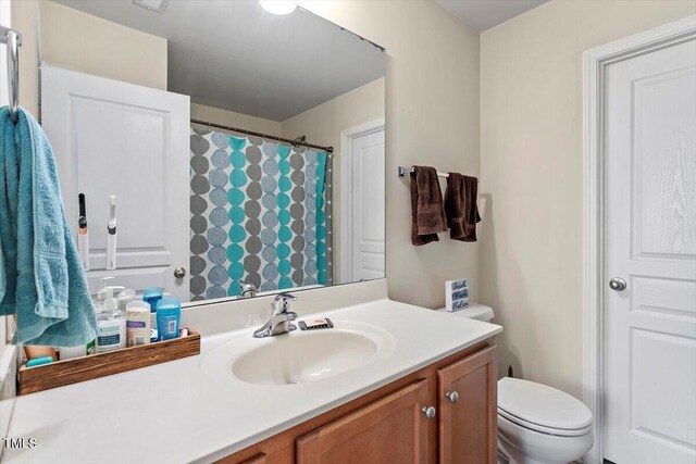 bathroom featuring toilet, vanity, and a shower with curtain