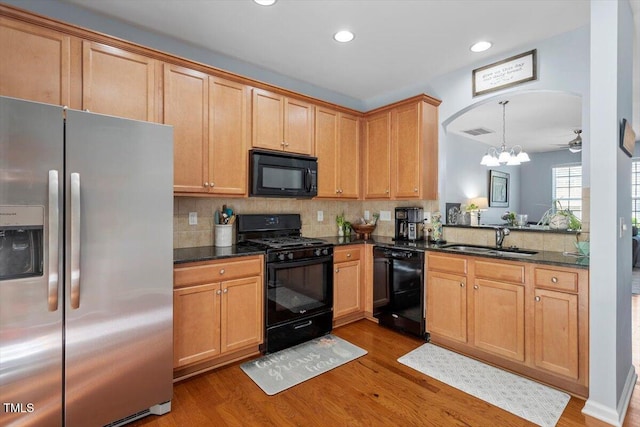 kitchen with black appliances, a sink, wood finished floors, a chandelier, and recessed lighting