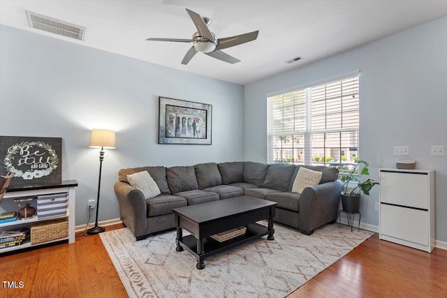 living area with a ceiling fan, wood finished floors, and baseboards