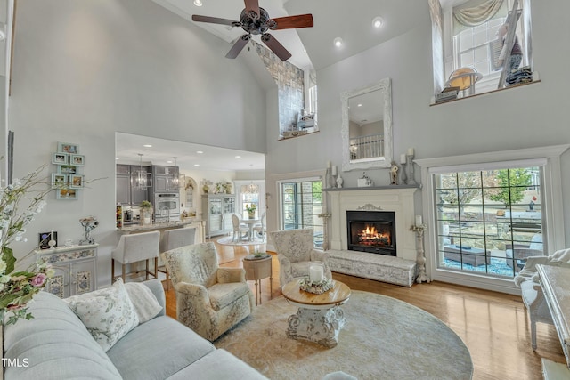 296 Shoreline Dr, Princeton, NC 27569 - living area with a ceiling fan, a warm lit fireplace, a towering ceiling, and wood finished floors