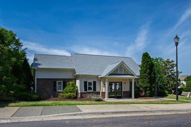 view of front of house featuring brick siding and a shingled roof