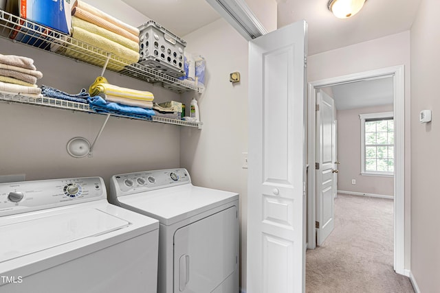laundry room with washer and clothes dryer, light colored carpet, and baseboards