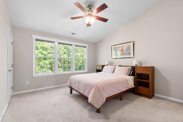 bedroom featuring baseboards, vaulted ceiling, light carpet, and a ceiling fan