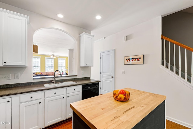 kitchen with a sink, black dishwasher, wood counters, white cabinetry, and recessed lighting
