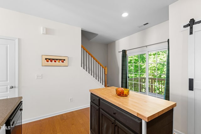 kitchen with butcher block counters, a barn door, light wood-style floors, baseboards, and recessed lighting
