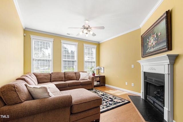 living room featuring a ceiling fan, ornamental molding, a fireplace with flush hearth, light wood-style flooring, and baseboards