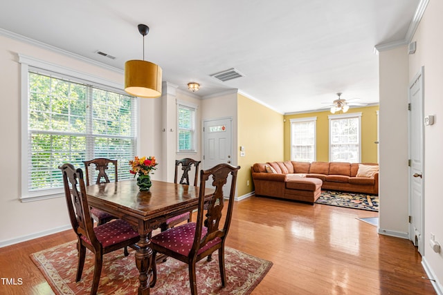 dining room featuring light wood finished floors, crown molding, baseboards, and a ceiling fan