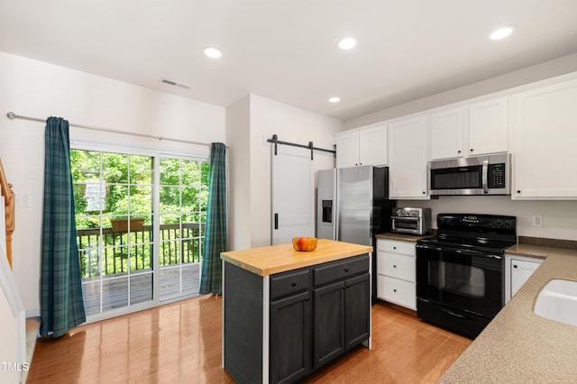 kitchen with appliances with stainless steel finishes, white cabinets, a barn door, wood counters, and recessed lighting