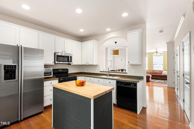 kitchen with black appliances, butcher block counters, a sink, white cabinetry, and light wood finished floors