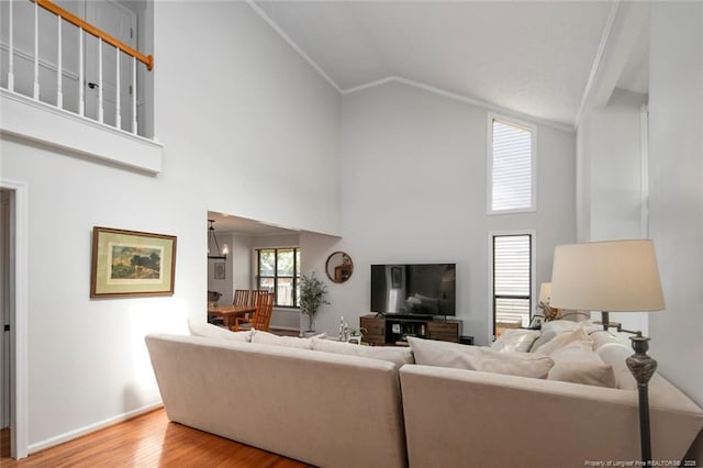living room with baseboards, an inviting chandelier, high vaulted ceiling, and wood finished floors