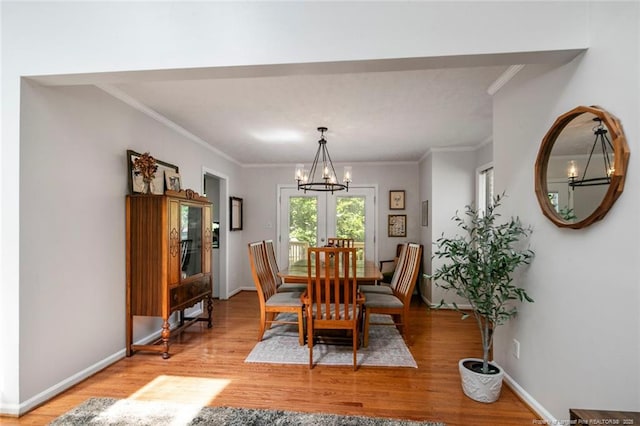 dining area featuring light wood finished floors, a chandelier, baseboards, and ornamental molding