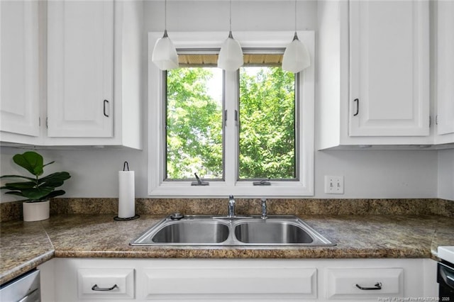 kitchen featuring dark countertops, white cabinetry, and a sink