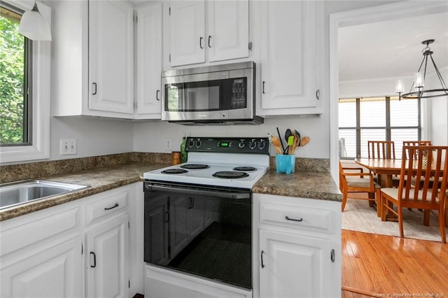 kitchen featuring white cabinets, electric range oven, stainless steel microwave, and a notable chandelier