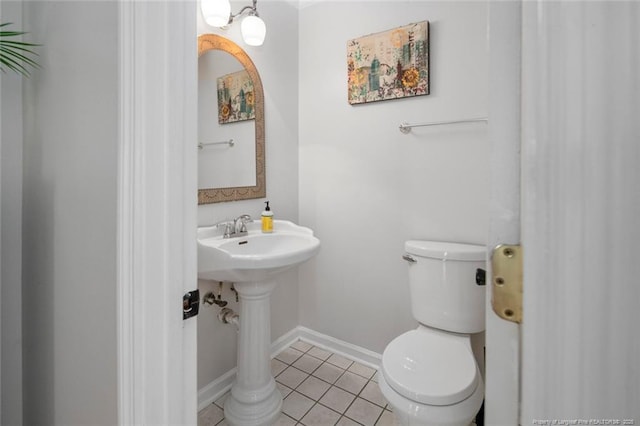 half bath with tile patterned flooring, toilet, and baseboards