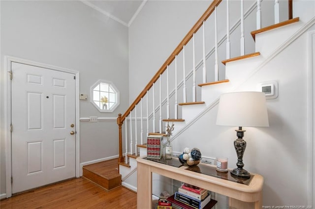 foyer entrance featuring baseboards, stairs, ornamental molding, and wood finished floors