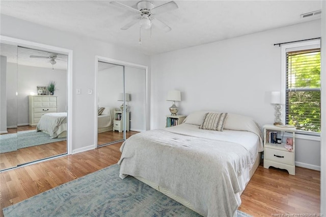 bedroom with multiple windows, visible vents, wood finished floors, and multiple closets