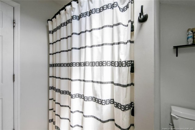 full bath with toilet and a shower with shower curtain