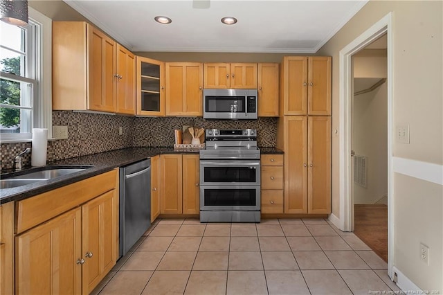 kitchen featuring appliances with stainless steel finishes, a sink, ornamental molding, and backsplash