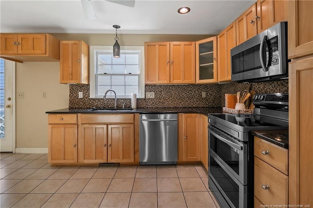 kitchen featuring light tile patterned floors, dark countertops, stainless steel appliances, and a sink