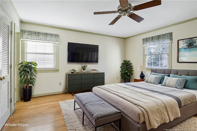 bedroom with baseboards, light wood finished floors, crown molding, and a ceiling fan