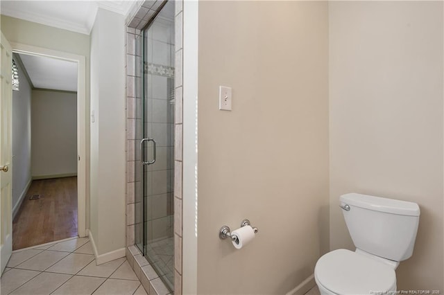 bathroom with toilet, baseboards, tiled shower, and ornamental molding