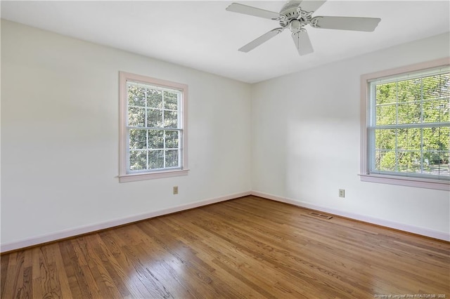 spare room with a wealth of natural light, visible vents, wood finished floors, and baseboards